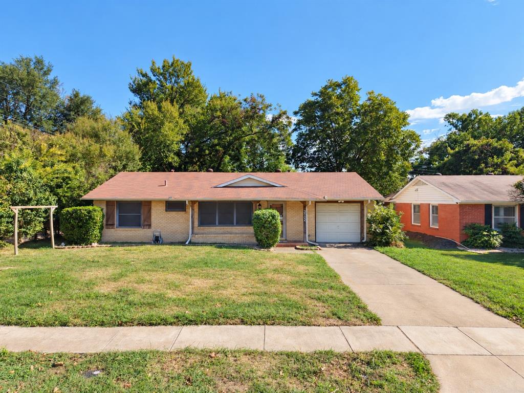 Single-story brick exterior featuring a shingled roof, attached one-car garage, concrete driveway, and front lawn Single-story brick exterior featuring a shingled roof, attached one-car garage, concrete driveway, and front lawn