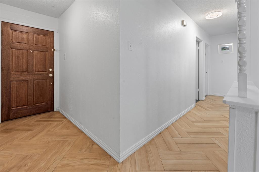 Entryway featuring a wood-finish door, herringbone-pattern wood-finish flooring, and a decorative white painted baluster Entryway featuring a wood-finish door, herringbone-pattern wood-finish flooring, and a decorative white painted baluster