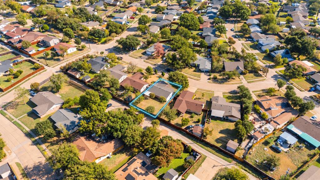 Aerial perspective of a residential property featuring a pitched roofline, an attached garage, a defined lot boundary, and established perimeter trees