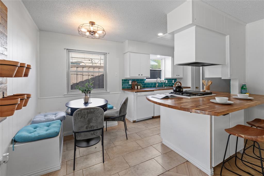 Kitchen featuring a butcher block peninsula with a gas cooktop, teal subway tile backsplash, white cabinetry, and ceramic tile flooring
