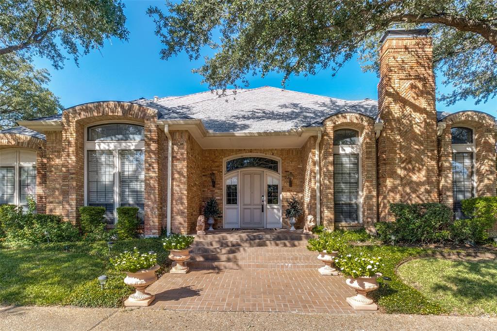 Brick exterior featuring an arched entryway, detailed masonry work, a covered front porch, and tall windows with transoms