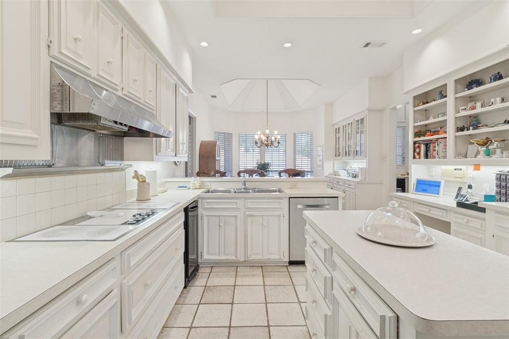 Kitchen featuring white cabinetry, center island, stainless steel range hood, built-in shelving, and tile flooring
