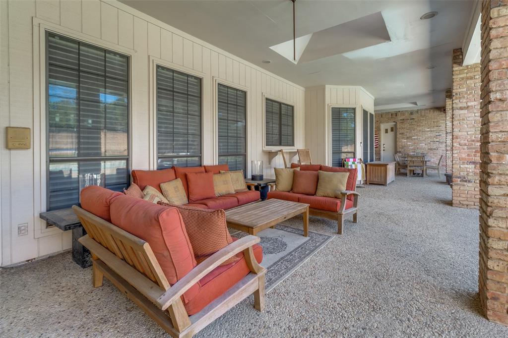 Covered patio featuring aggregate concrete flooring, recessed lighting, brick column accents, and vertical exterior siding