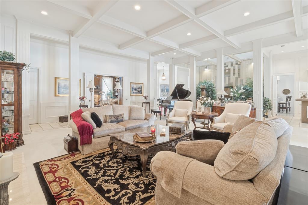 Coffered ceiling with recessed lighting, wainscoting, and polished stone flooring