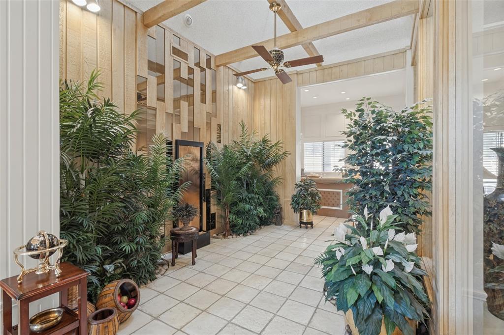 Interior space featuring vertical wood paneling, decorative mirror accents, exposed ceiling beams, a ceiling fan, and tile flooring