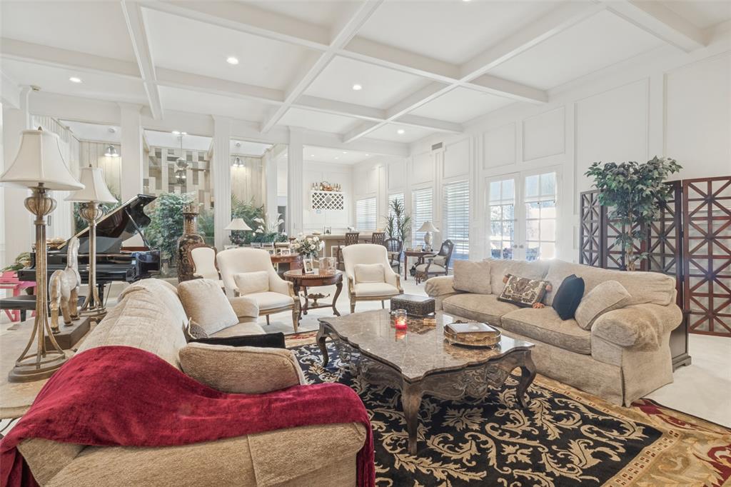 Spacious room featuring a coffered ceiling, recessed lighting, wall molding, and multiple glass-paned doors