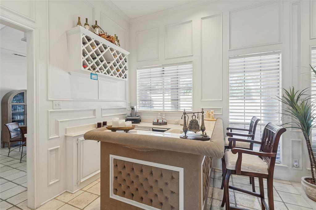 Built-in wet bar featuring stone-finish countertop, grid-style bottle storage, and decorative wall molding