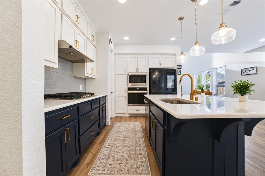 Beautifully kitchen featuring navy cabinetry, gold accents, stainless steel appliances, and a spacious island with quartz countertops. Beautifully kitchen featuring navy cabinetry, gold accents, stainless steel appliances, and a spacious island with quartz countertops.