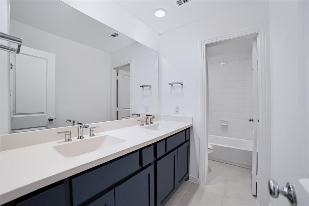 Upstairs guest bathroom featuring a convenient double-sink vanity.
