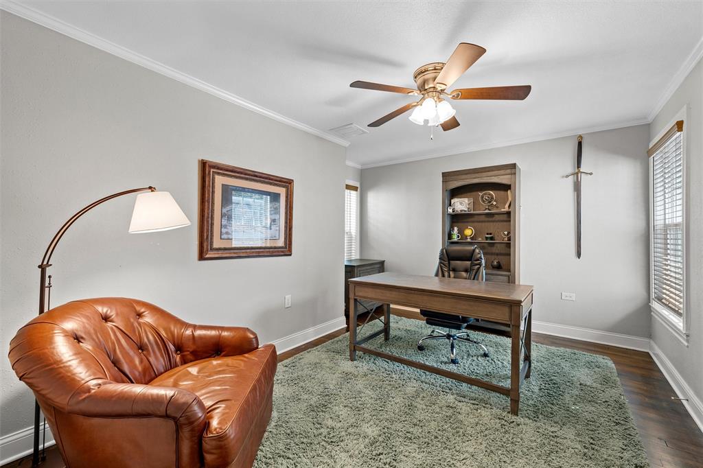 Room featuring wood-finish flooring, built-in shelving, a ceiling fan with light fixture, and windows with horizontal blinds