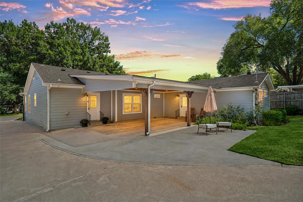 Exterior featuring horizontal lap siding, a sprawling concrete driveway, an expansive covered carport with decorative wood support posts, and a manicured lawn