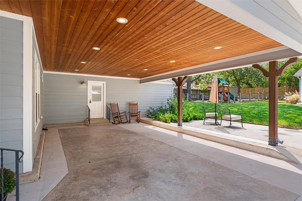 Covered patio featuring a wood-plank ceiling with recessed lighting, concrete flooring, and decorative timber support columns