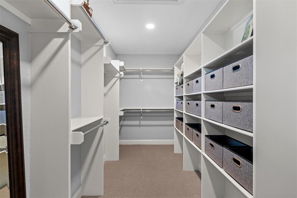 Walk-in closet featuring extensive built-in white shelving, multiple hanging rods, and recessed lighting