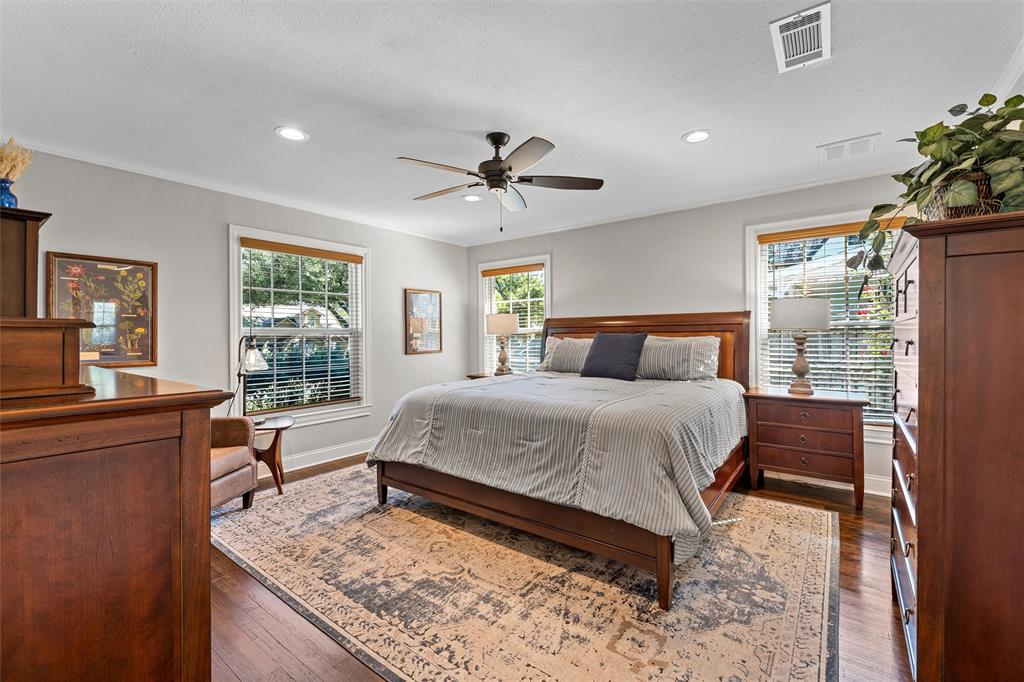 Spacious room featuring wood-finish flooring, recessed lighting, a central ceiling fan, and multi-pane windows with wood-trim detailing
