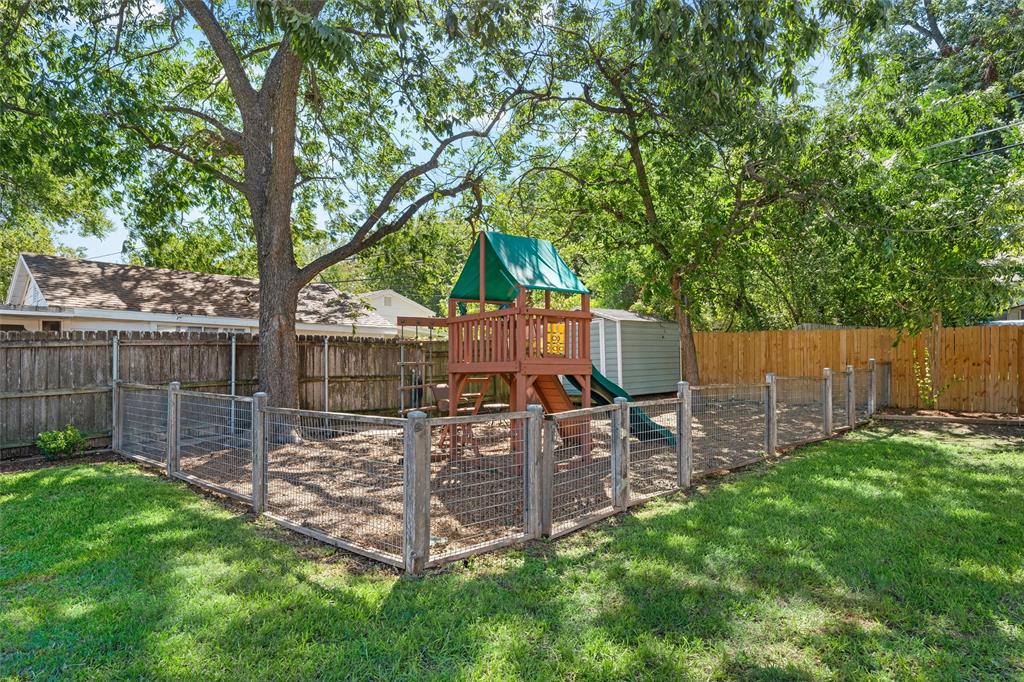 Fenced backyard featuring wood-post wire mesh enclosure, mature tree canopy, and detached storage structure