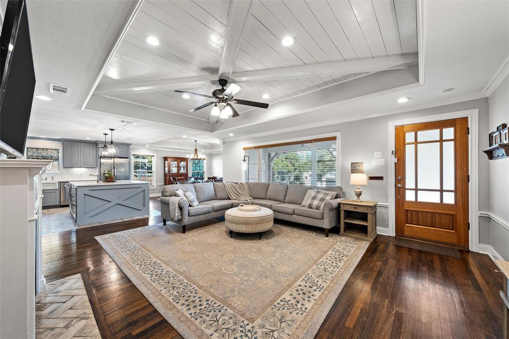 Tray ceiling with planked detail, wood-finish flooring, central ceiling fan with integrated lighting, recessed lighting, and a multi-pane glass-panel entry door