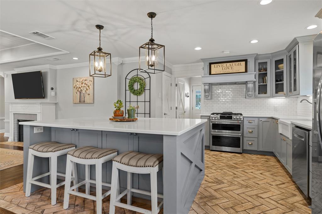 Kitchen featuring a center island with quartz countertops, herringbone-pattern brick flooring, stainless steel range, white subway tile backsplash, and decorative pendant lighting