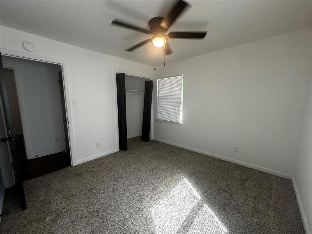Neutral-toned carpeting, ceiling-mounted light fixture with fan, and closet with built-in shelving
