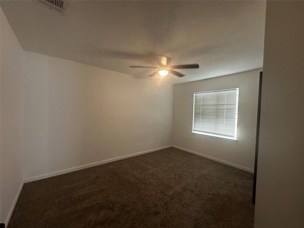 Neutral interior space featuring carpeted flooring, a ceiling fan with integrated lighting, and horizontal window blinds
