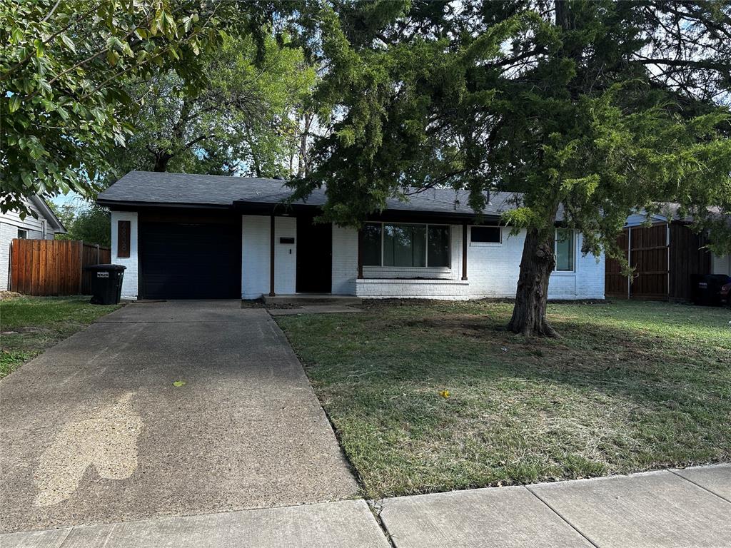 Single-story exterior featuring painted brick siding, asphalt shingle roofing, an attached garage, and a concrete driveway