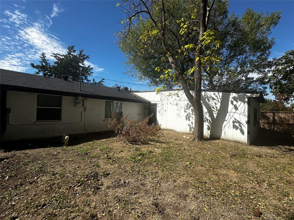 Exterior featuring painted brick and vertical siding, asphalt shingle roofing, and a wood privacy fence