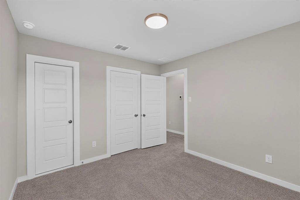 Neutral interior featuring gray carpeting, soft gray wall paint, five-panel interior doors, and a flush-mount circular ceiling fixture