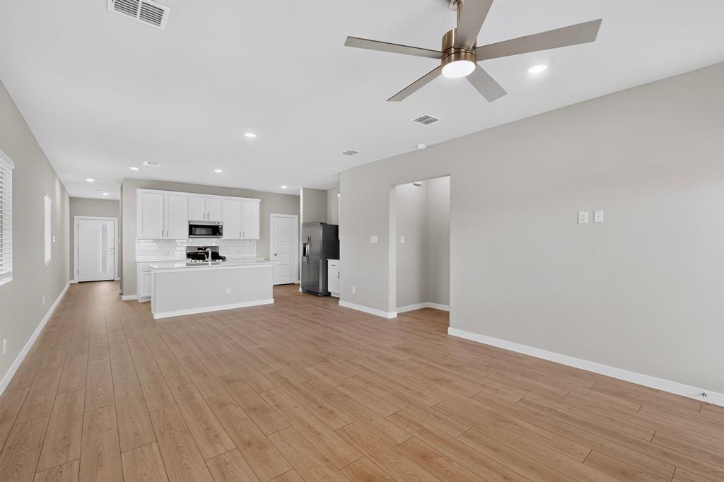 Open-concept interior featuring wood-finish flooring, recessed lighting, a modern ceiling fan, and white cabinetry Open-concept interior featuring wood-finish flooring, recessed lighting, a modern ceiling fan, and white cabinetry