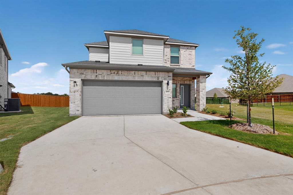 Two-story exterior featuring a light-toned brick and horizontal siding facade, concrete driveway, attached garage, and covered entryway Two-story exterior featuring a light-toned brick and horizontal siding facade, concrete driveway, attached garage, and covered entryway