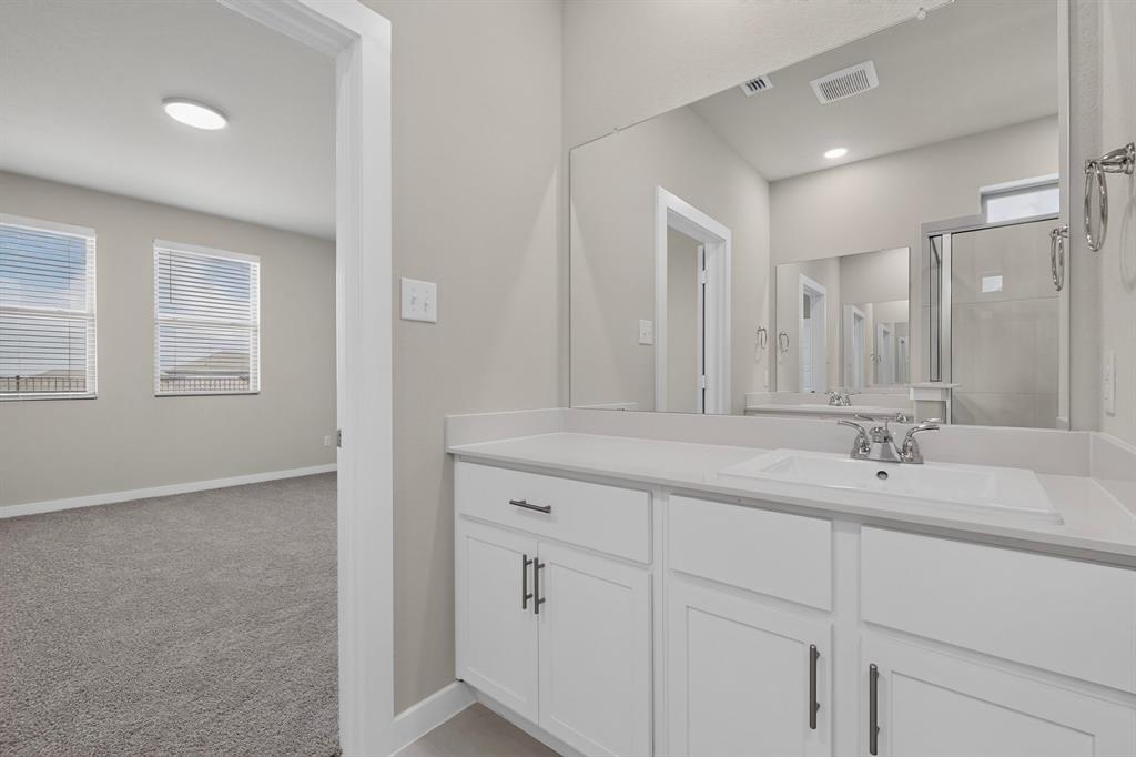 Bathroom vanity featuring white cabinetry, dark hardware, and an integrated countertop sink with a chrome faucet