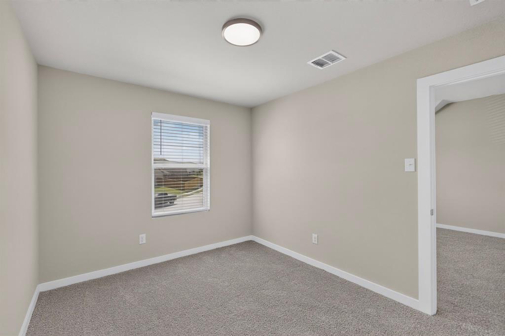 Neutral-toned interior space featuring wall-to-wall carpeting, a single-hung window with horizontal blinds, and a central flush-mount ceiling light fixture