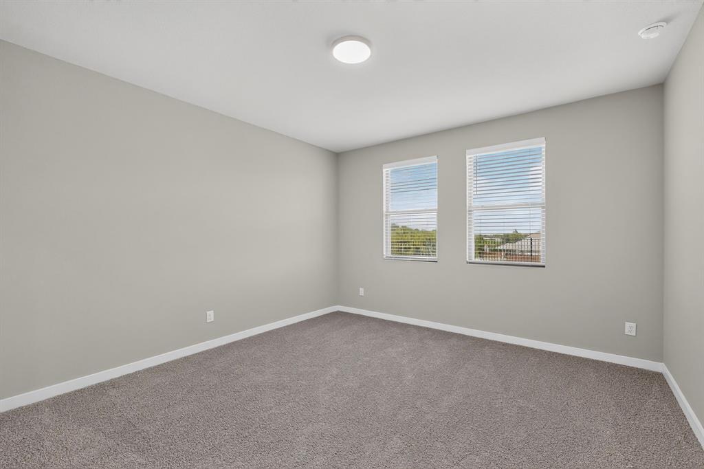 Neutral-toned interior space featuring neutral wall paint, wall-to-wall carpeting, dual windows, and a flush-mount ceiling light fixture