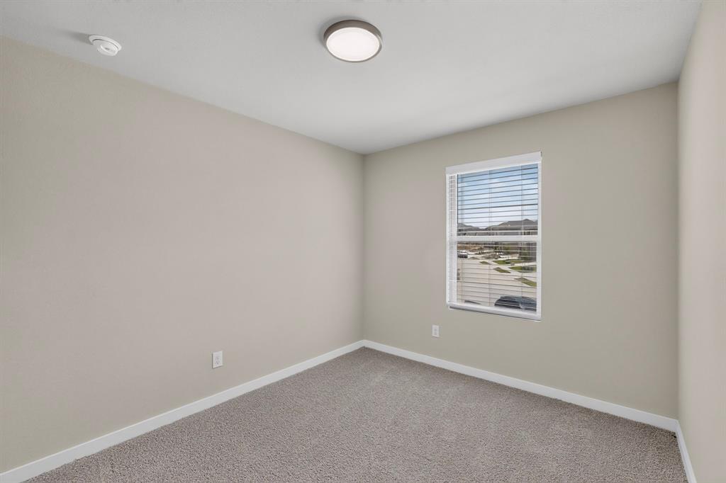 Neutral-toned interior room featuring wall-to-wall carpeting, a single-pane window with horizontal blinds, and a central flush-mount ceiling light fixture