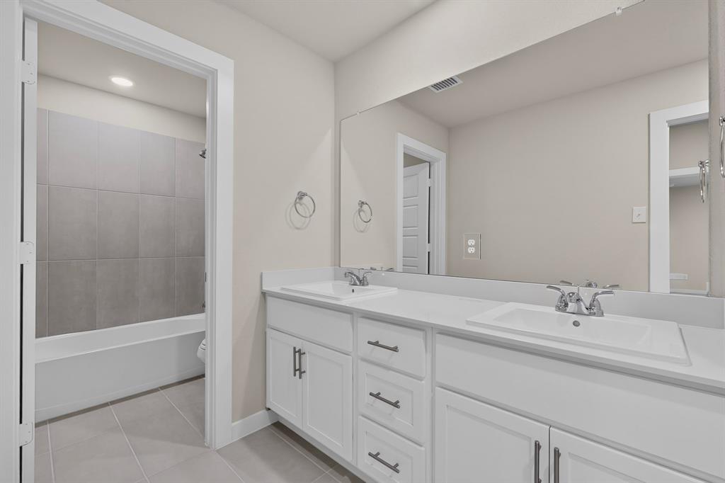 Dual-sink vanity with white cabinetry, solid-surface countertop, polished chrome fixtures, and a full-width vanity mirror