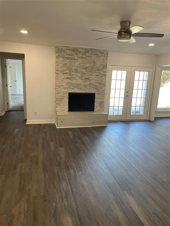 Fireplace featuring a floor-to-ceiling stacked stone surround, wood-finish flooring, recessed lighting, ceiling fan, and French doors