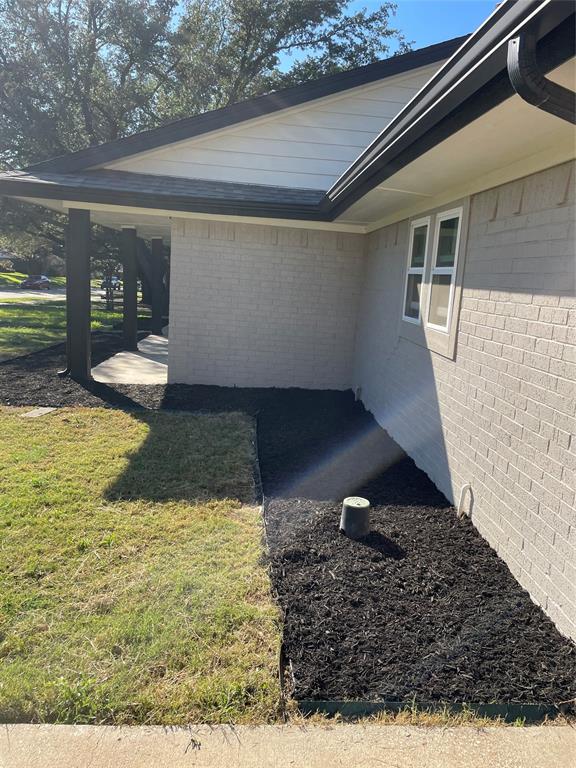 Exterior featuring a neutral-toned brick facade, dark-toned trim, a concrete porch, and landscaped mulch beds Exterior featuring a neutral-toned brick facade, dark-toned trim, a concrete porch, and landscaped mulch beds