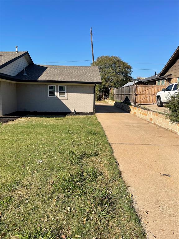 Exterior elevation featuring masonry siding, asphalt shingle roofing, a concrete driveway, and a stone retaining wall Exterior elevation featuring masonry siding, asphalt shingle roofing, a concrete driveway, and a stone retaining wall