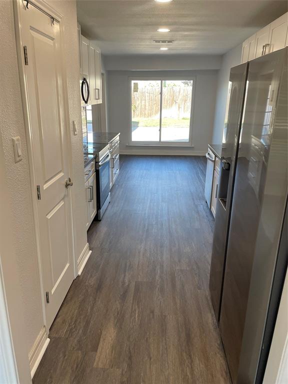 Galley kitchen featuring white cabinetry, wood-finish flooring, recessed lighting, and a sliding glass door