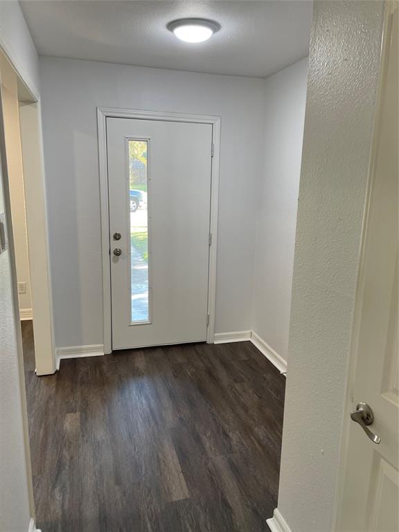 Entryway featuring wood-finish flooring, a white front door with a vertical glass insert, and a flush-mount overhead light fixture Entryway featuring wood-finish flooring, a white front door with a vertical glass insert, and a flush-mount overhead light fixture