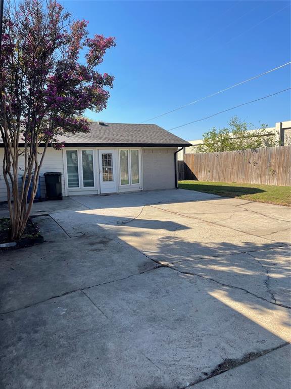 Exterior space featuring a concrete patio, wood fencing, and a mature flowering tree