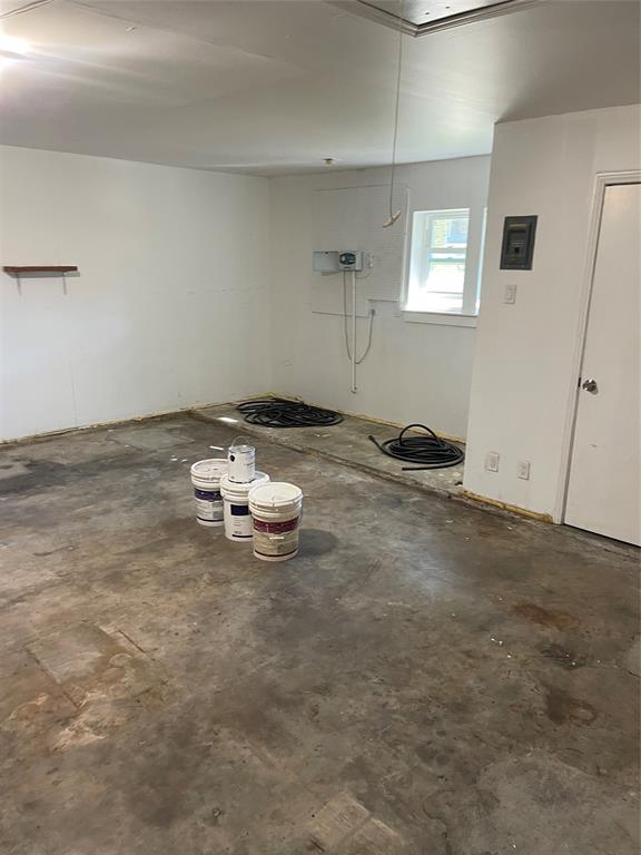 Interior space featuring white-painted walls, concrete flooring, a single window, and a built-in wall shelf