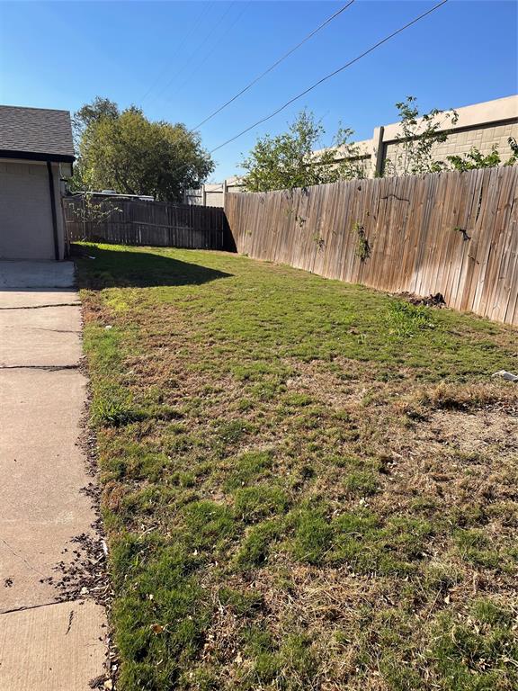 Exterior side yard featuring a concrete walkway and wood privacy fencing