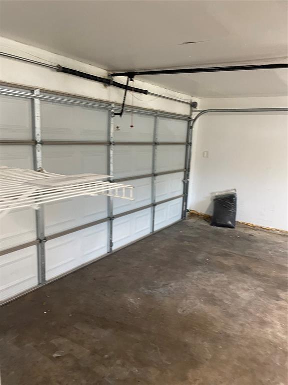 Garage featuring a sectional overhead door, automatic door opener mechanism, and built-in wire shelving
