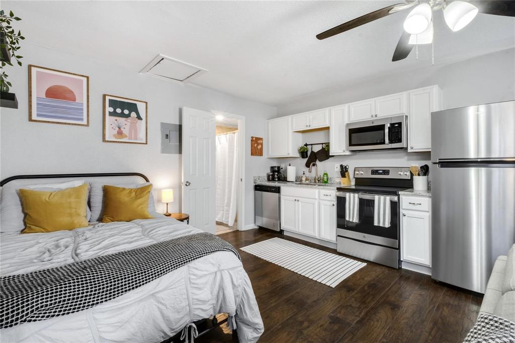 White cabinetry, stainless steel appliances, wood-finish flooring, and ceiling fan