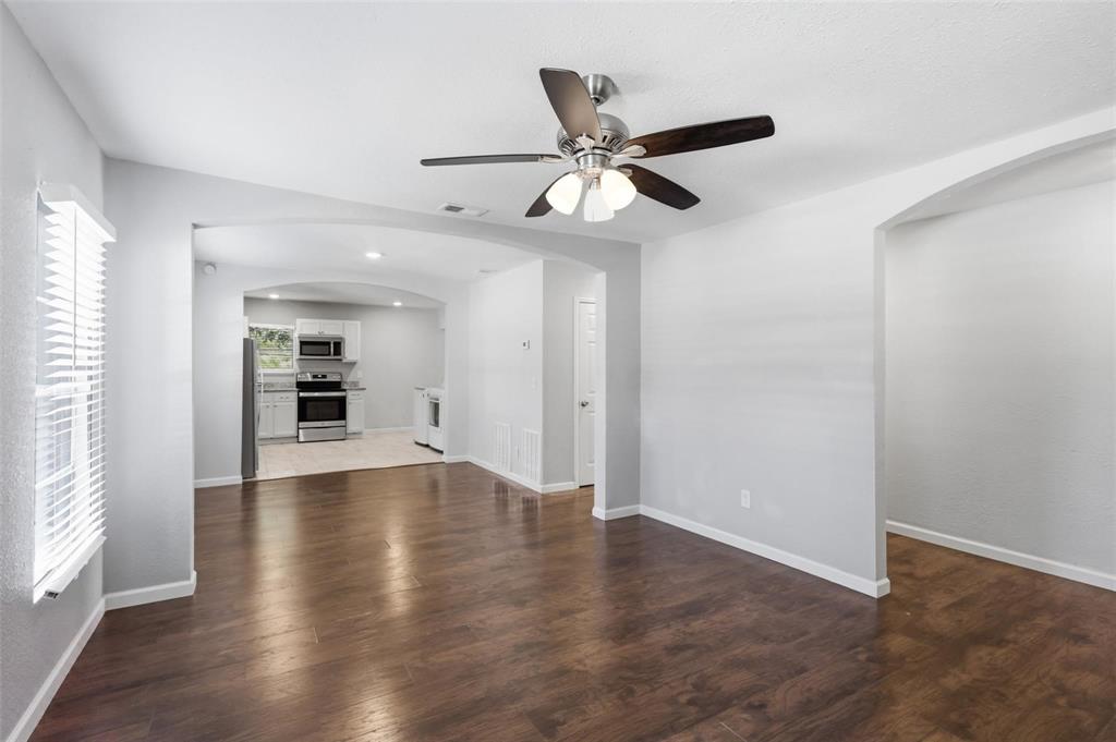 Interior featuring wood-finish flooring, arched doorways, a ceiling fan with integrated lighting, and horizontal blinds Interior featuring wood-finish flooring, arched doorways, a ceiling fan with integrated lighting, and horizontal blinds
