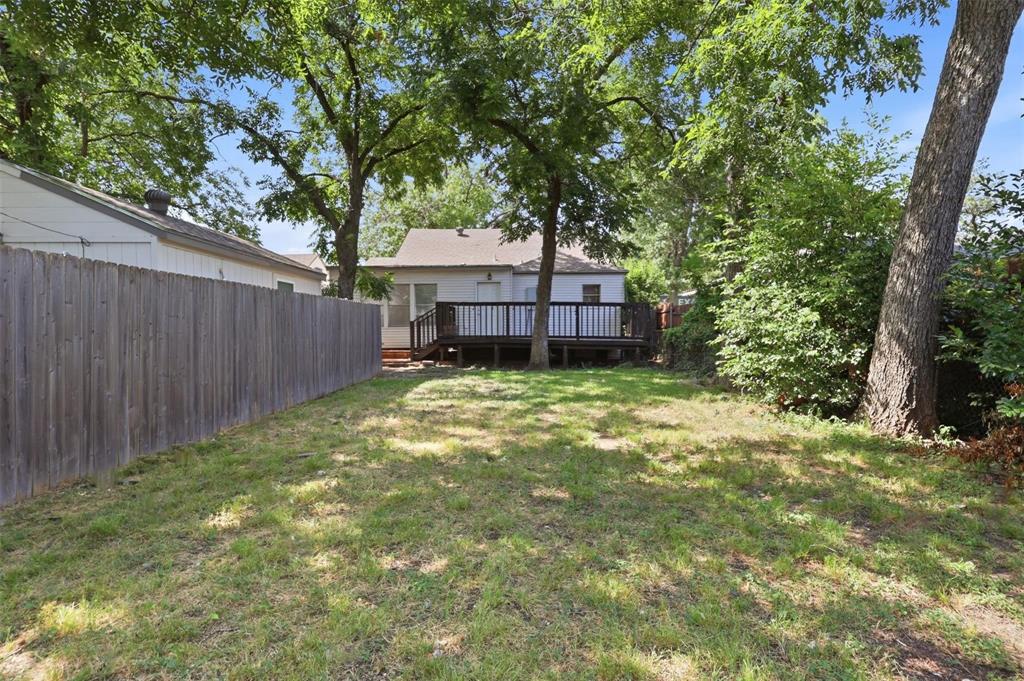 Backyard featuring a wood deck, vertical board fencing, and mature trees