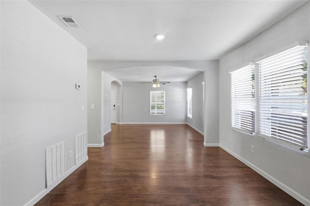 Open-concept interior featuring wood-finish flooring, an arched entryway, recessed lighting, and horizontal window blinds Open-concept interior featuring wood-finish flooring, an arched entryway, recessed lighting, and horizontal window blinds