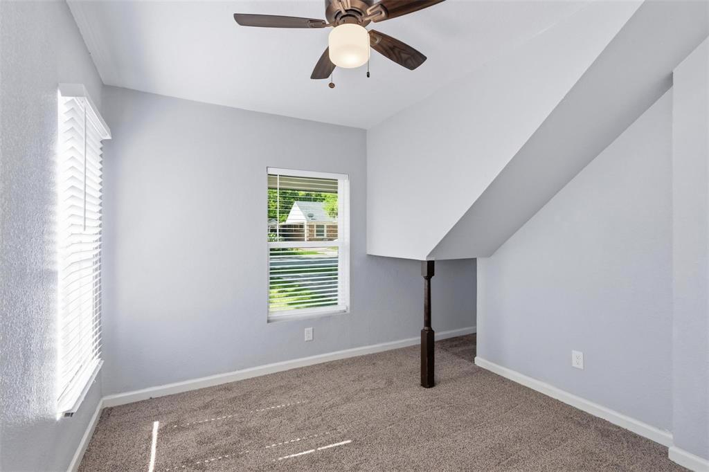 Neutral wall coloring with carpeted flooring, a ceiling fan with integrated lighting, and a dark-toned decorative support column