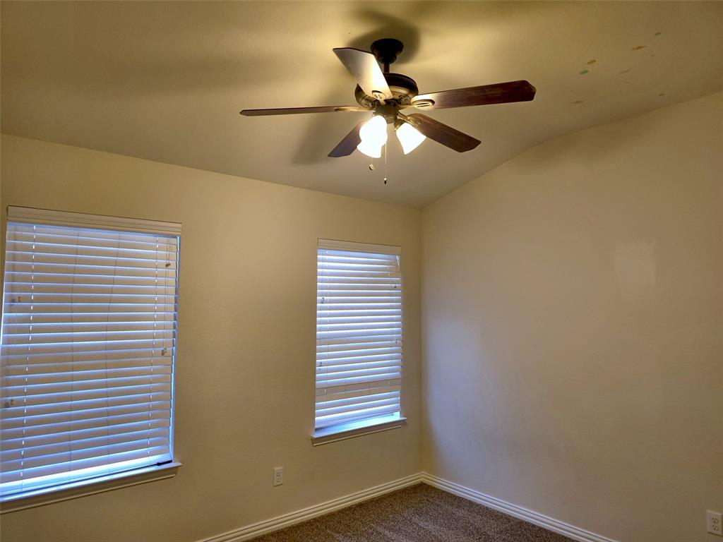 Interior room featuring neutral wall tones, multi-blade ceiling fan with integrated lighting, and two windows outfitted with horizontal blinds