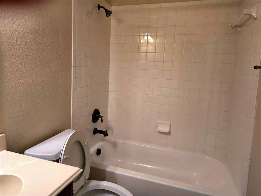 Full-size bathtub with white tile surround, matte black showerhead and faucet, built-in soap dish, and vanity with integrated countertop Full-size bathtub with white tile surround, matte black showerhead and faucet, built-in soap dish, and vanity with integrated countertop