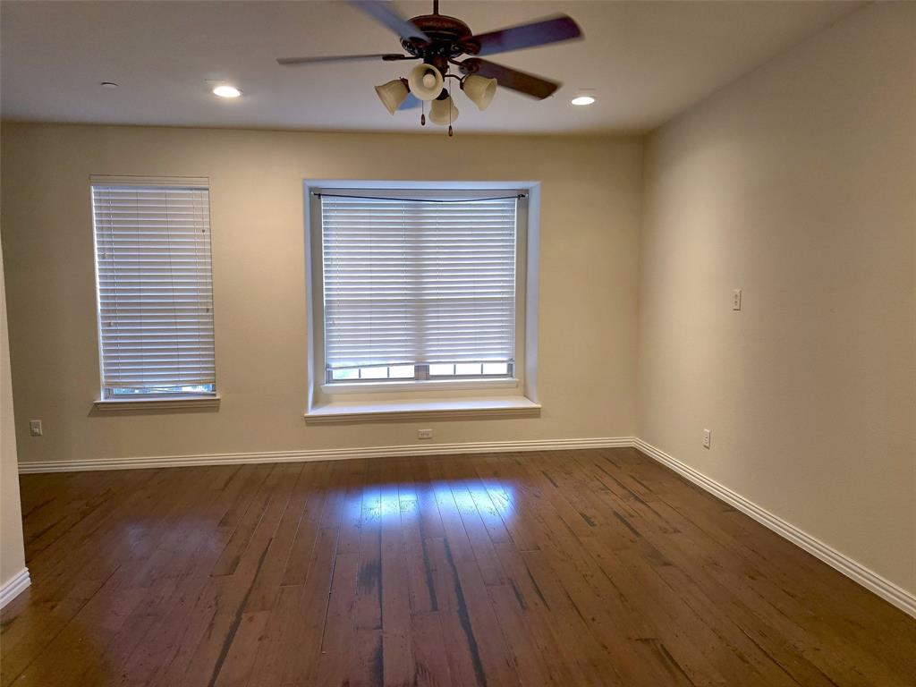 Room featuring wood-finish flooring, recessed lighting, a ceiling fan with integrated lighting, and a bay window with a sill